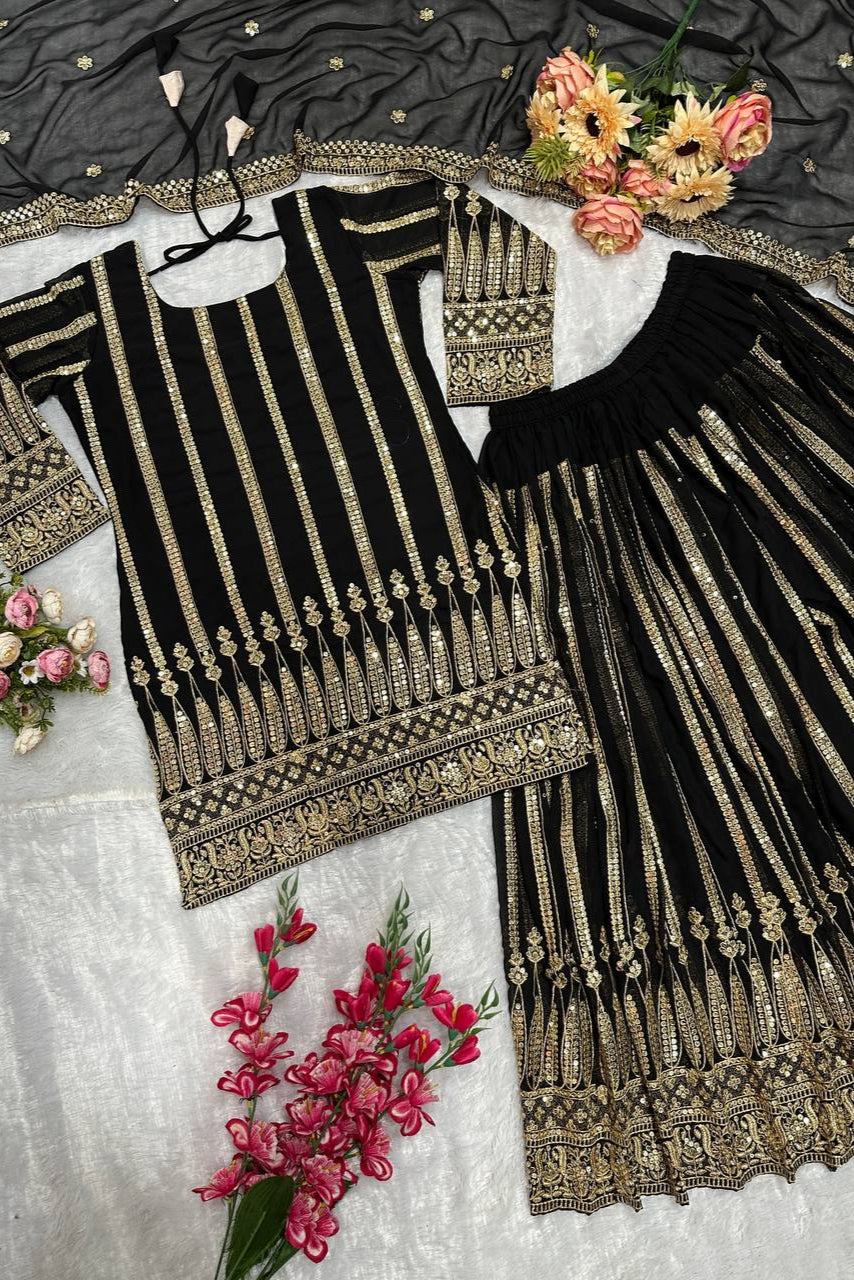 Black and gold embroidered traditional outfit with floral decorations on a textured surface.