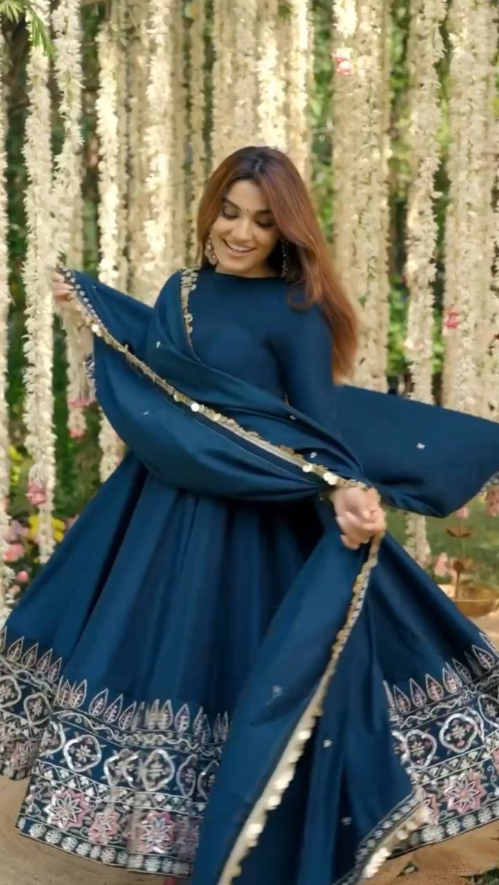 Woman in a blue traditional outfit with floral decorations in the background